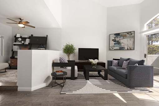 A living room with a grey couch, a black TV, and a striped rug.