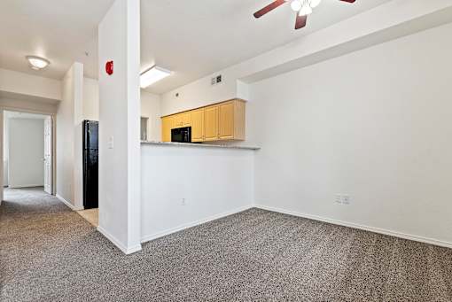 A room with a ceiling fan and a kitchenette.