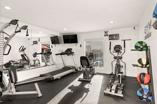 A gym with a variety of equipment including treadmills, weights, and exercise balls.