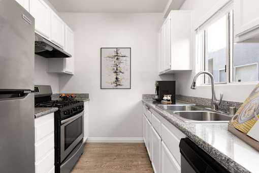 A modern kitchen with a stove, sink, and cabinets.