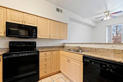 A kitchen with black appliances and wooden cabinets.