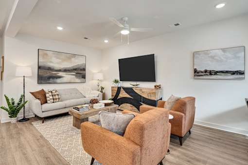 A living room with a couch, chairs, and a television