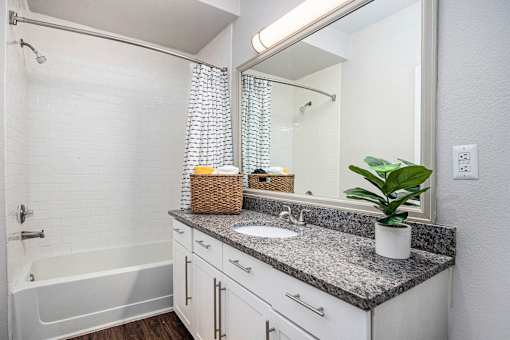 A bathroom with a white tub, sink, and a mirror.