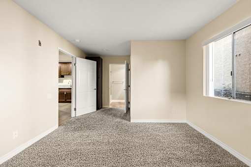 A room with a carpeted floor and a window on the right side.