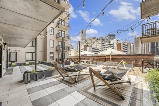 a rooftop terrace with lounge chairs and a city in the background
