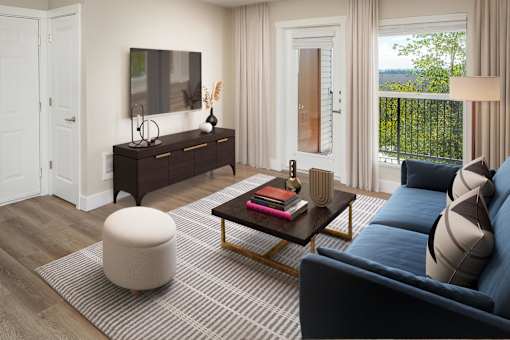 A living room with a dark blue sofa, a wooden coffee table, a white ottoman, and a flat-screen TV mounted on the wall.