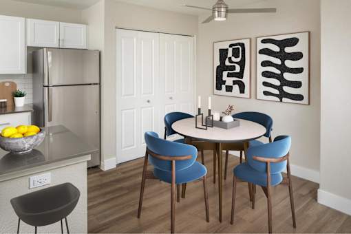 A modern kitchen with a round table and blue chairs.