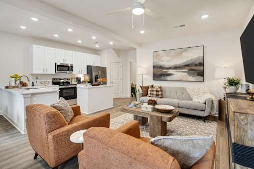 A modern living room with a kitchen in the background.