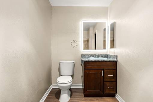 A white toilet sits in a bathroom next to a wooden cabinet.