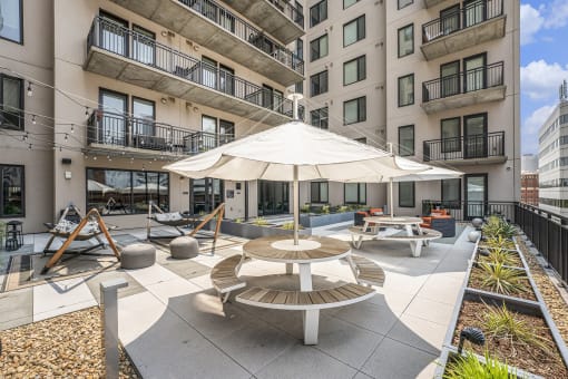 an outdoor patio with tables and an umbrella in an apartment building