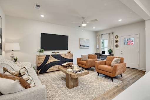 A living room with a sofa, a wooden coffee table, and a mounted TV on the wall.