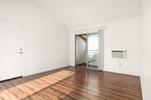 A room with a white door and a window with a view of trees.