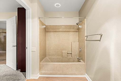 A bathroom with a walk-in shower and a doorway leading to another room.