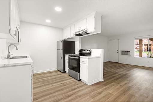 A modern kitchen with wooden floors and white appliances.