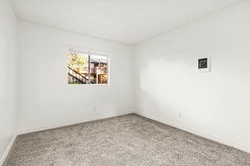 A room with a window showing a view of a building outside.