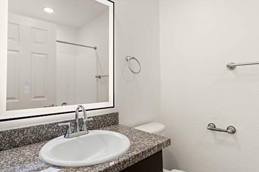 A bathroom with a sink, mirror, and towel rack.