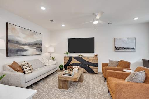 A living room with a white couch, a coffee table, and a television.