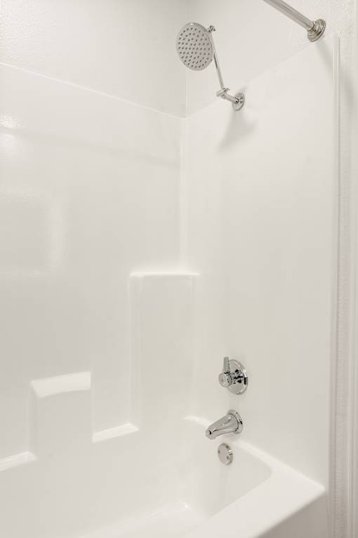 A white bathtub with a shower head and faucet.