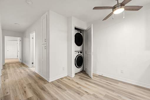 A room with a white ceiling and a fan, and a washing machine in the corner.
