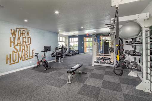 A gym with a variety of equipment including a rowing machine, a bench, and a weight rack.