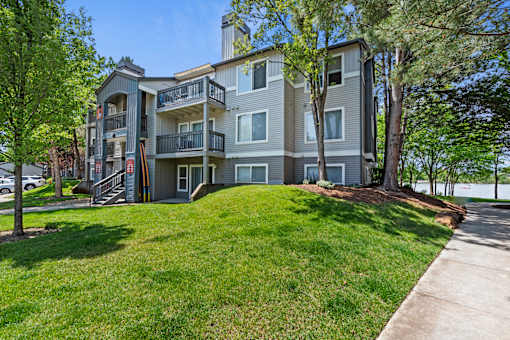 A large apartment building with a grassy front yard.