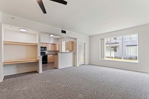 Empty room with a fan on the ceiling and a window showing a building outside.