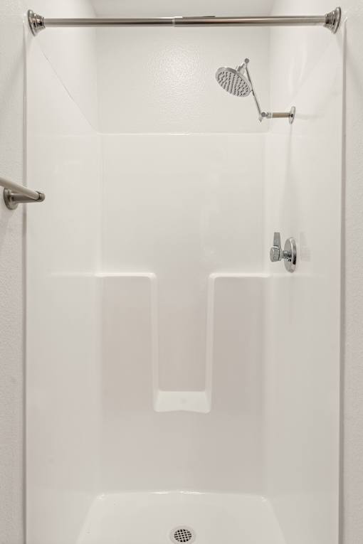 A white shower stall with a shower head and a hand held shower.