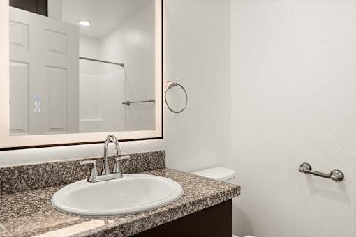 A bathroom with a sink, mirror, and toilet.