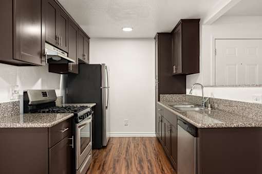 A kitchen with brown cabinets and a black refrigerator.