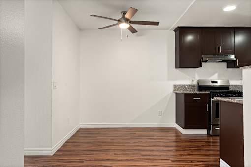 A kitchen with brown cabinets and a ceiling fan.