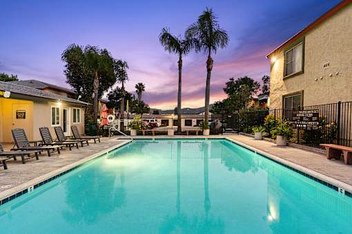 A swimming pool surrounded by palm trees and lounge chairs.