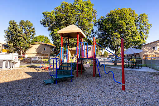 A playground with a red and blue swing set and a yellow canopy.