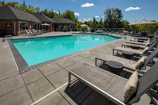 A large outdoor swimming pool surrounded by sun loungers and umbrellas.