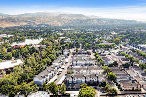 A bird's eye view of a residential area with houses and a lake in the distance.