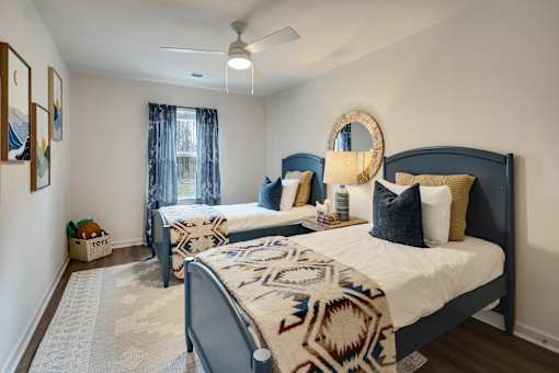 A bedroom with two beds and a ceiling fan.