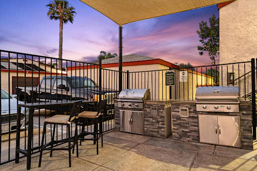 A patio with a table and chairs and a grill.