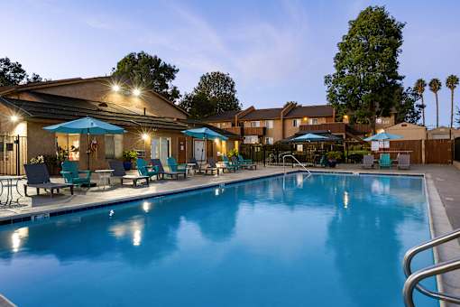 A swimming pool surrounded by lounge chairs and umbrellas.