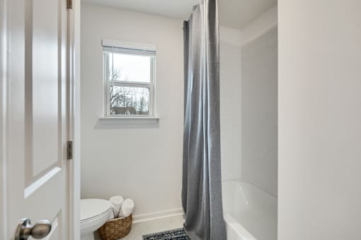 A bathroom with a white toilet and a grey shower curtain