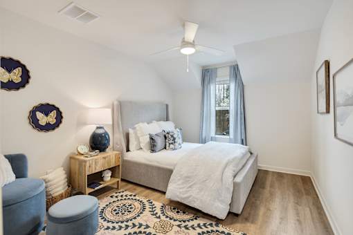 A bedroom with a bed, a chair, and a rug.