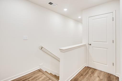 A white door is on the right side of a hallway.