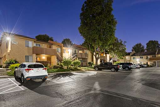 A parking lot with cars and apartment buildings in the background.
