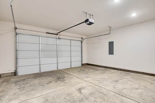 A garage with a white door and a concrete floor.