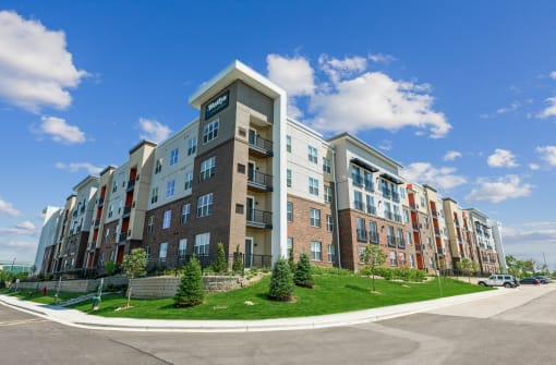 an apartment building on a grassy hill with a blue sky in the background