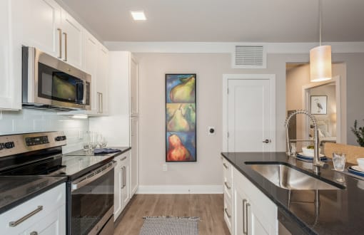 a kitchen with black counter tops and white cabinets