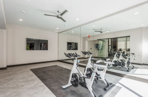 a gym with treadmills and other exercise equipment in a glass walled room