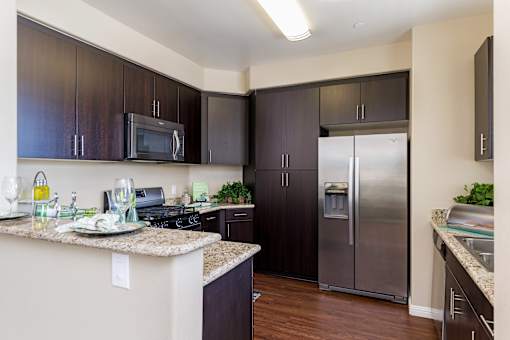 A kitchen with dark brown cabinets and a granite counter top.