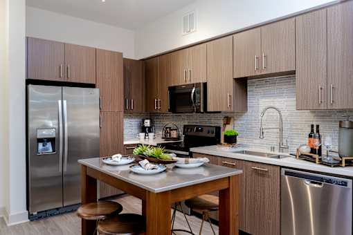 A modern kitchen with a stainless steel refrigerator and a wooden dining table set with plates.