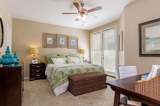 A bedroom with a bed, a chair, and a ceiling fan.