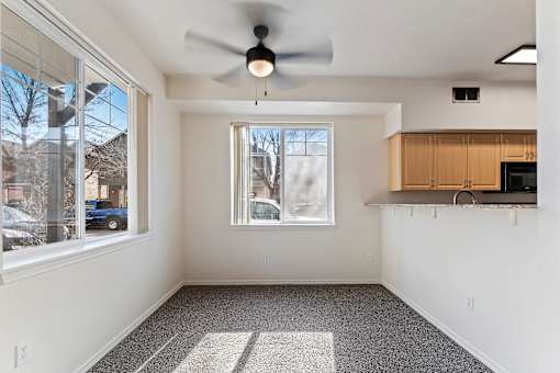 A room with a ceiling fan and a window overlooking a parking lot.