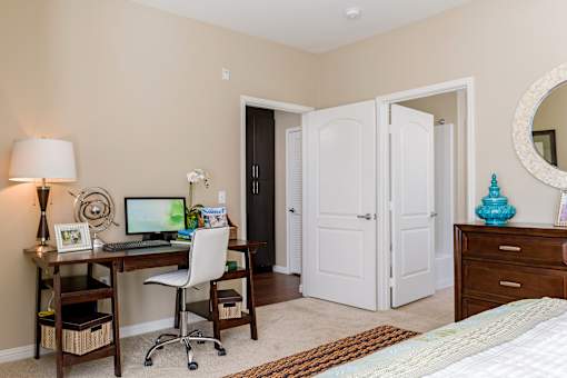 A room with a desk, chair, and bed.